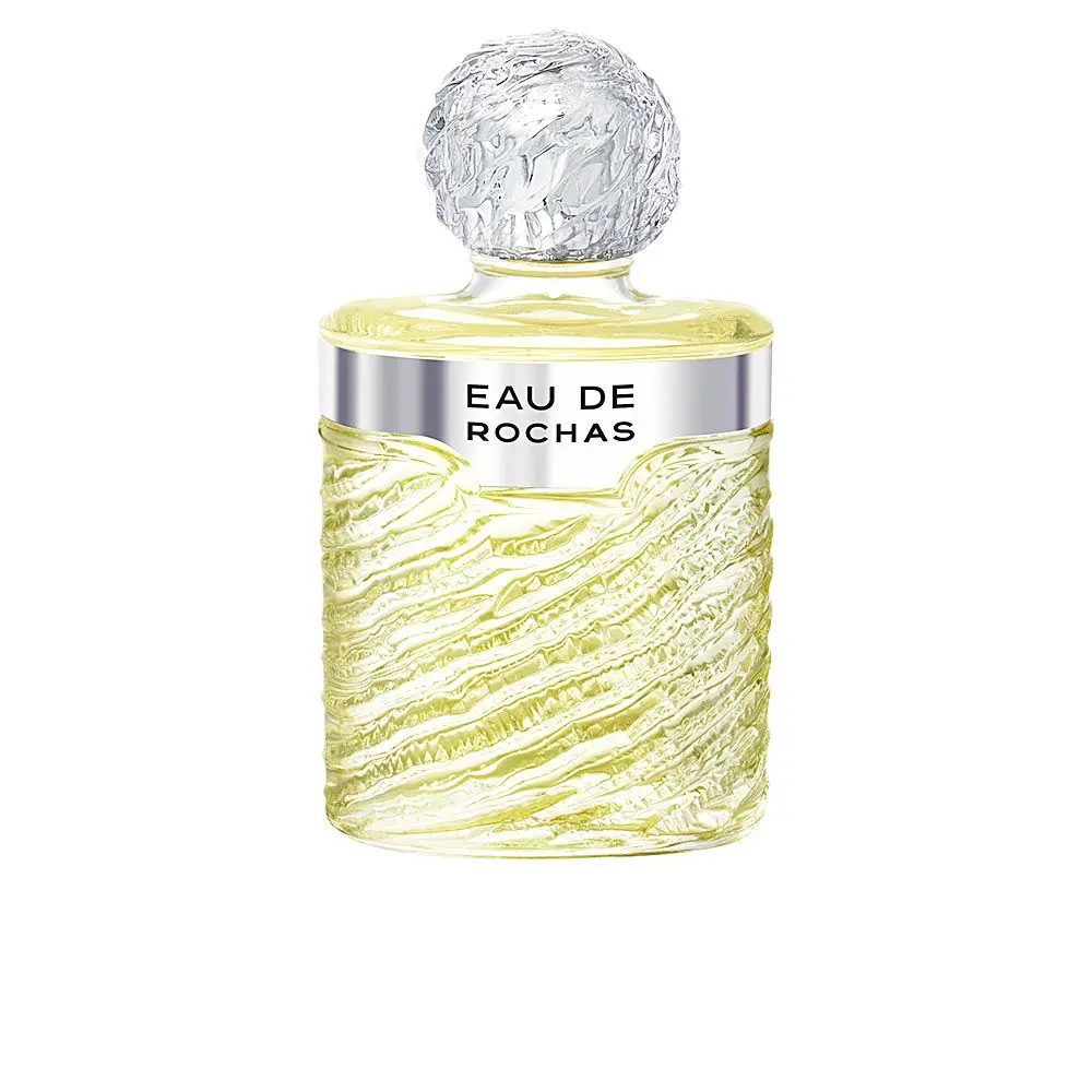 Eau de Rochas EDT 100ml spray en un frasco de cristal transparente con ondas texturizadas, tapón redondo transparente, líquido amarillo claro y "EAU DE ROCHAS" en una banda plateada cerca de la parte superior.