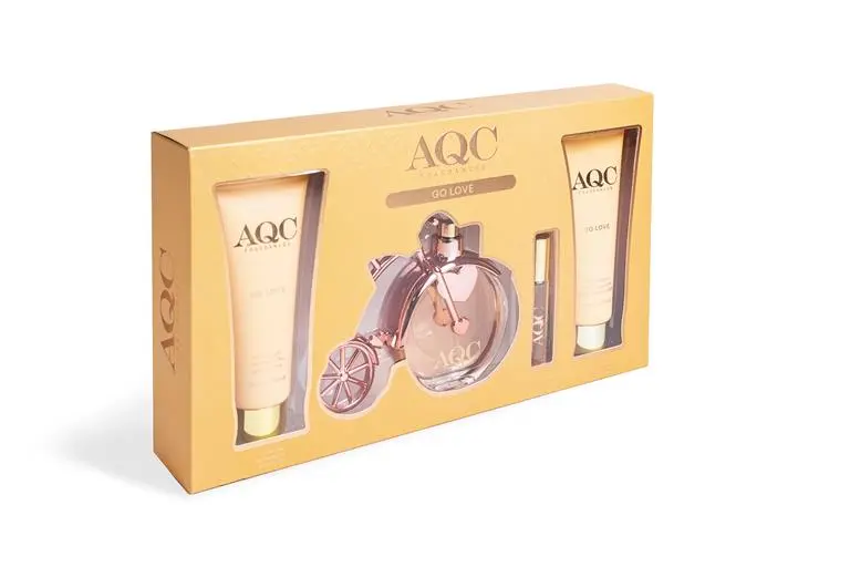 Un estuche de regalo dorado con el perfume IDC Lady Secret zapato rojo EDP 100ml, un frasco rosa, dos tubos de loción y un pequeño pulverizador: un elegante set ideal para los fans de Lady Secret o Zapato Rojo. Se muestra sobre fondo blanco.