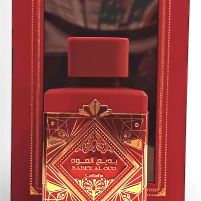 badee al oud sublime front center El frasco negro y dorado de Lattafa Asad Zanzibar EDP 100 ml se encuentra delante de su caja a juego, ambas adornadas con intrincados motivos geométricos y escritura árabe.