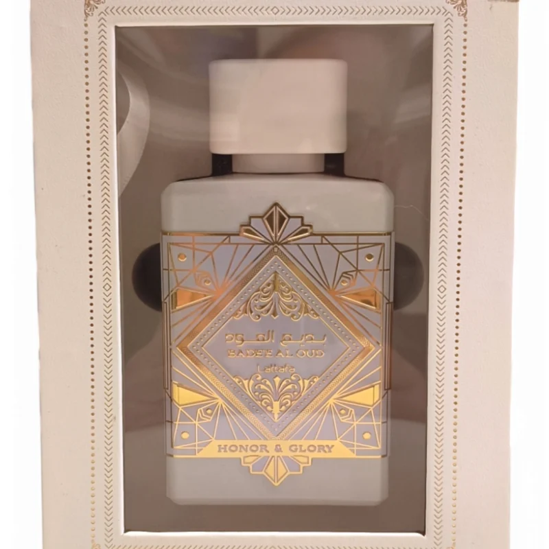 honor and glory boxed Un frasco de perfume en caja etiquetado Lattafa Asad Zanzibar EDP 100ml, con diseños geométricos dorados sobre fondo blanco y visibles a través de una ventana en el envase.