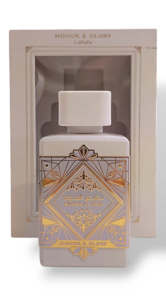 Un frasco de perfume blanco con diseños geométricos dorados y texto en árabe, etiquetado Lattafa Asad Zanzibar EDP 100ml, se muestra delante de su caja abierta a juego con decoraciones ornamentales.