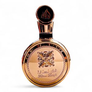 Un frasco redondo de perfume dorado con la etiqueta Lattafa Fakhar Gold Extrait EDP 100ml, con escritura árabe grabada, detalles ornamentales, un tapón decorativo y un diseño central inspirado en una mariposa.