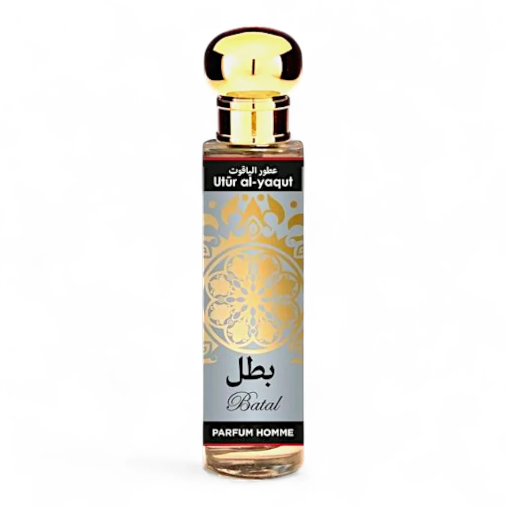 Un frasco de perfume de vidrio transparente con tapón dorado, etiquetado Utür al-yaqut Batal hombre EDP 30ml en inglés y árabe, presenta un diseño decorativo dorado sobre fondo gris.