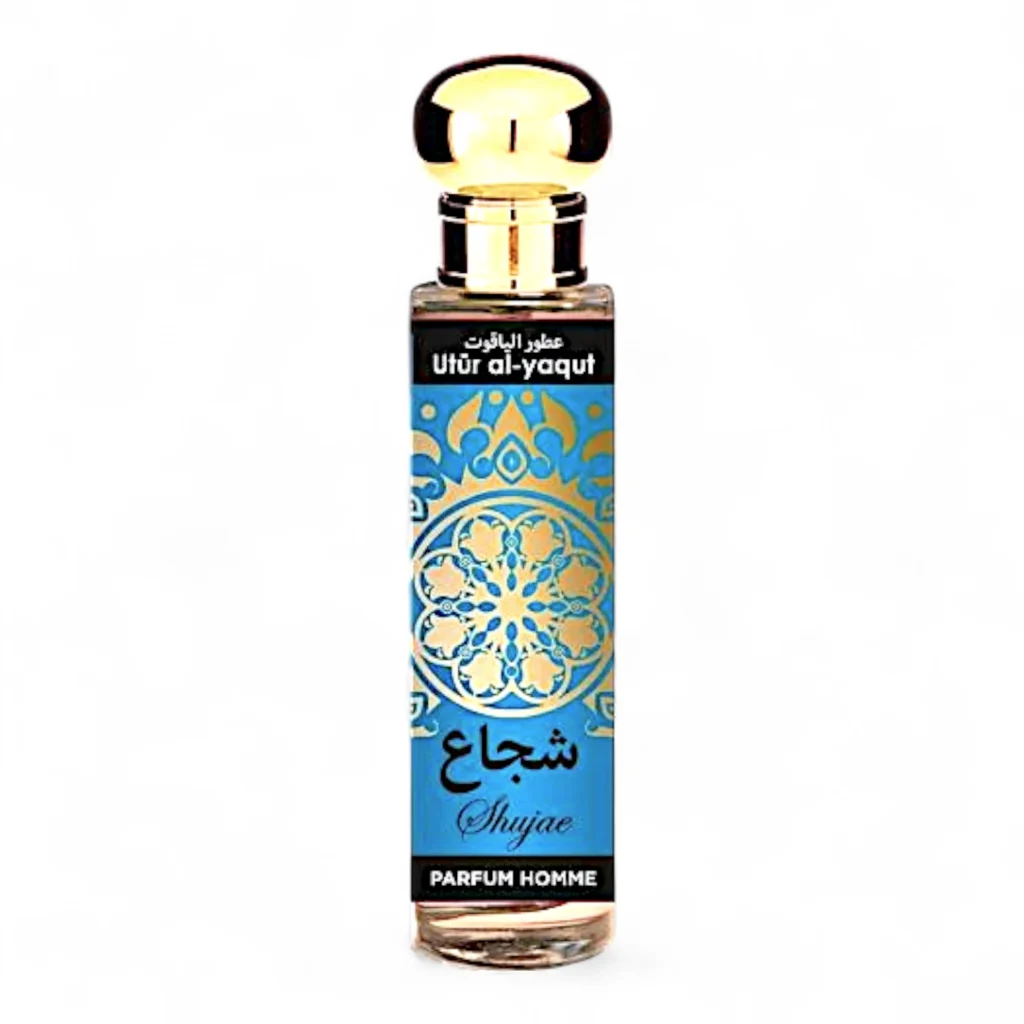 Un frasco de perfume de vidrio transparente con tapón dorado, etiquetado Utür al-yaqut Shujae hombre EDP 30ml en árabe e inglés, presenta un diseño ornamentado en azul y dorado y "Parfum Homme" en la parte inferior.