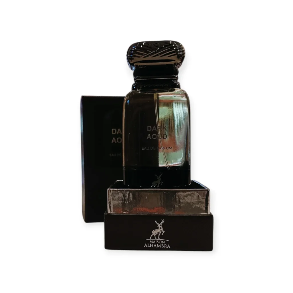 Un frasco de perfume de vidrio oscuro con la etiqueta Dark Aoud se encuentra delante de su caja negra, con el logotipo de Maison Alhambra y un león visibles en la parte delantera. El tapón del frasco es texturado y ornamentado. Un frasco de perfume de vidrio oscuro con la etiqueta Dark Aoud se encuentra delante de su caja negra, con el logotipo de Maison Alhambra y un león visibles en la parte delantera. El tapón del frasco es texturado y ornamentado.