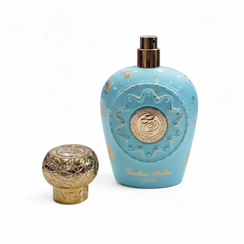 Frasco de perfume turquesa con detalles dorados y un decorativo tapón redondo dorado al lado. El frasco presenta detalles ornamentales y escritura árabe dorada, y lleva la etiqueta «Opulent Dubai Lattafa». Frasco de perfume turquesa con detalles dorados y un decorativo tapón redondo dorado al lado. El frasco presenta detalles ornamentales y escritura árabe dorada, y lleva la etiqueta "Opulent Dubai Lattafa".