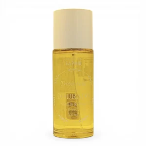 Frasco transparente de Perfums Saphir Dourado Tropic Gold Vanilla & Musk Hair & Body oil, 100 ml, con tapón blanco y líquido amarillo en el interior, fotografiado sobre un fondo blanco liso.