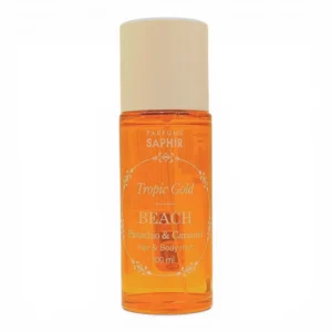 Un frasco de 100 ml de Parfums Saphir Tropic Gold BEACH Pistachio & Caramel Hair & Body Mist con un líquido ámbar anaranjado y un tapón beige, fotografiado sobre un fondo blanco.