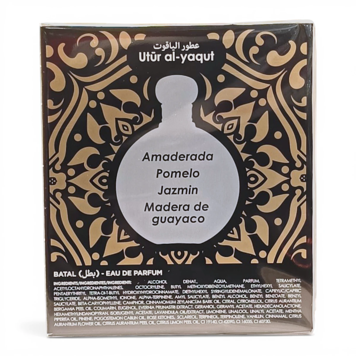 Una caja de perfume etiquetada como Utür al-yaqut presenta motivos ornamentados en oro y negro, con notas de fragancia enumeradas: Amaderada, Pomelo, Jazmín, Madera de guayaco. Los ingredientes están impresos en la parte inferior.
