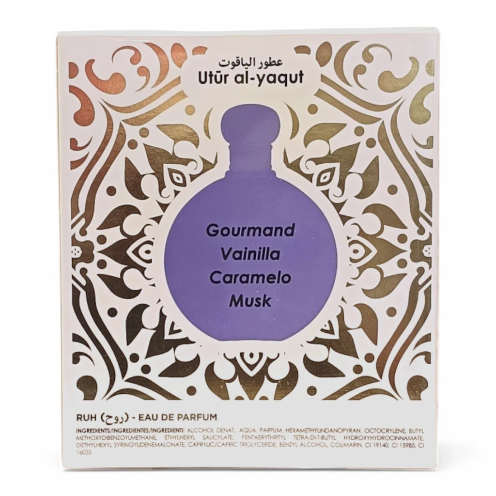Caja de perfume con motivos ornamentales dorados, etiquetada Utūr al-yaqūt en la parte superior. En el centro aparece una ilustración de un frasco morado con las palabras Gourmand Vainilla Caramelo Musk. En la parte inferior se lee RUH Eau de Parfum. Caja de perfume con motivos ornamentales dorados, etiquetada Utūr al-yaqūt en la parte superior. En el centro aparece una ilustración de un frasco morado con las palabras Gourmand Vainilla Caramelo Musk. En la parte inferior se lee RUH Eau de Parfum.
