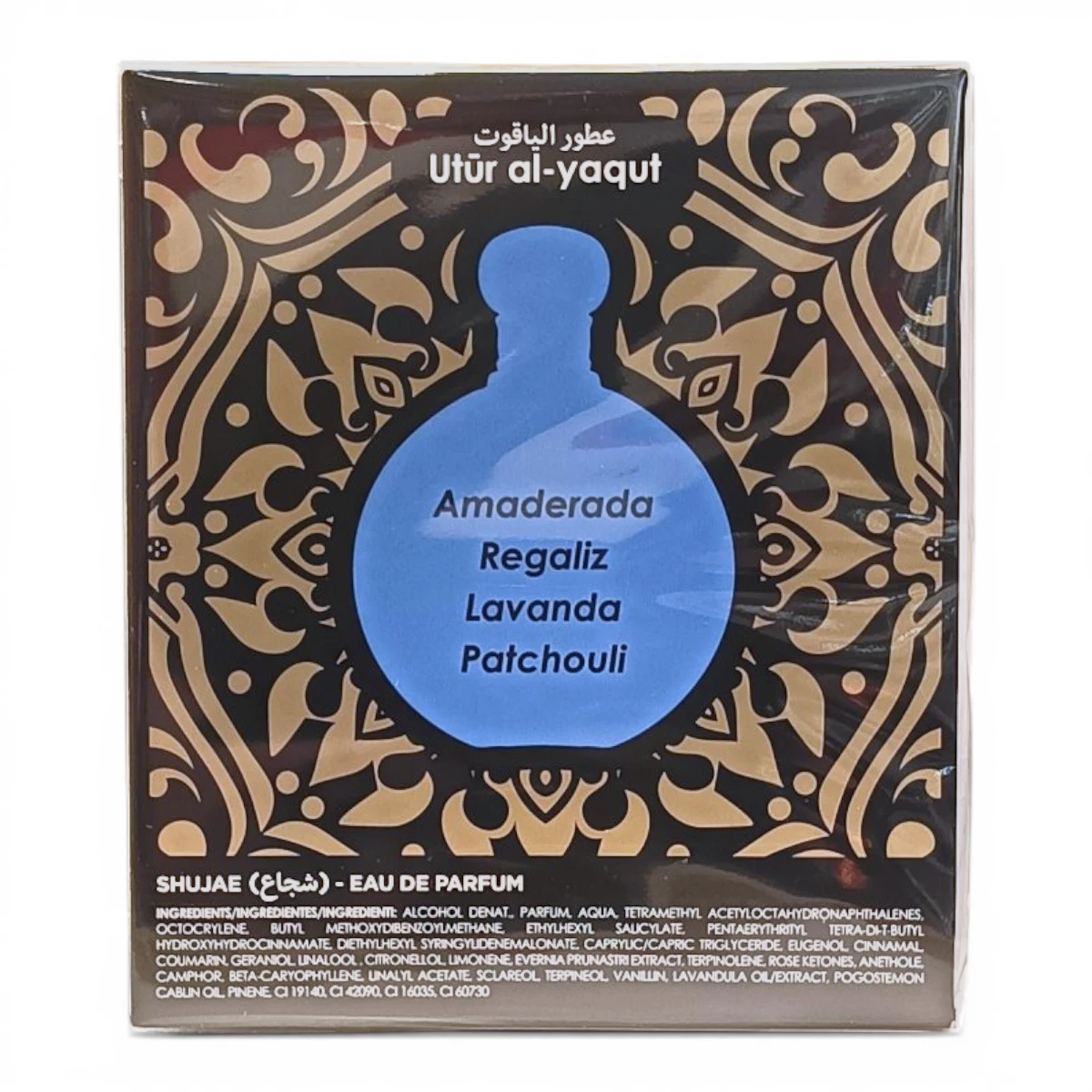 Una caja de perfume con la etiqueta Utúr al-yaqut presenta un diseño de frasco azul con las notas olfativas: Amaderada, Regaliz, Lavanda y Pachulí, sobre un fondo decorativo negro y dorado.