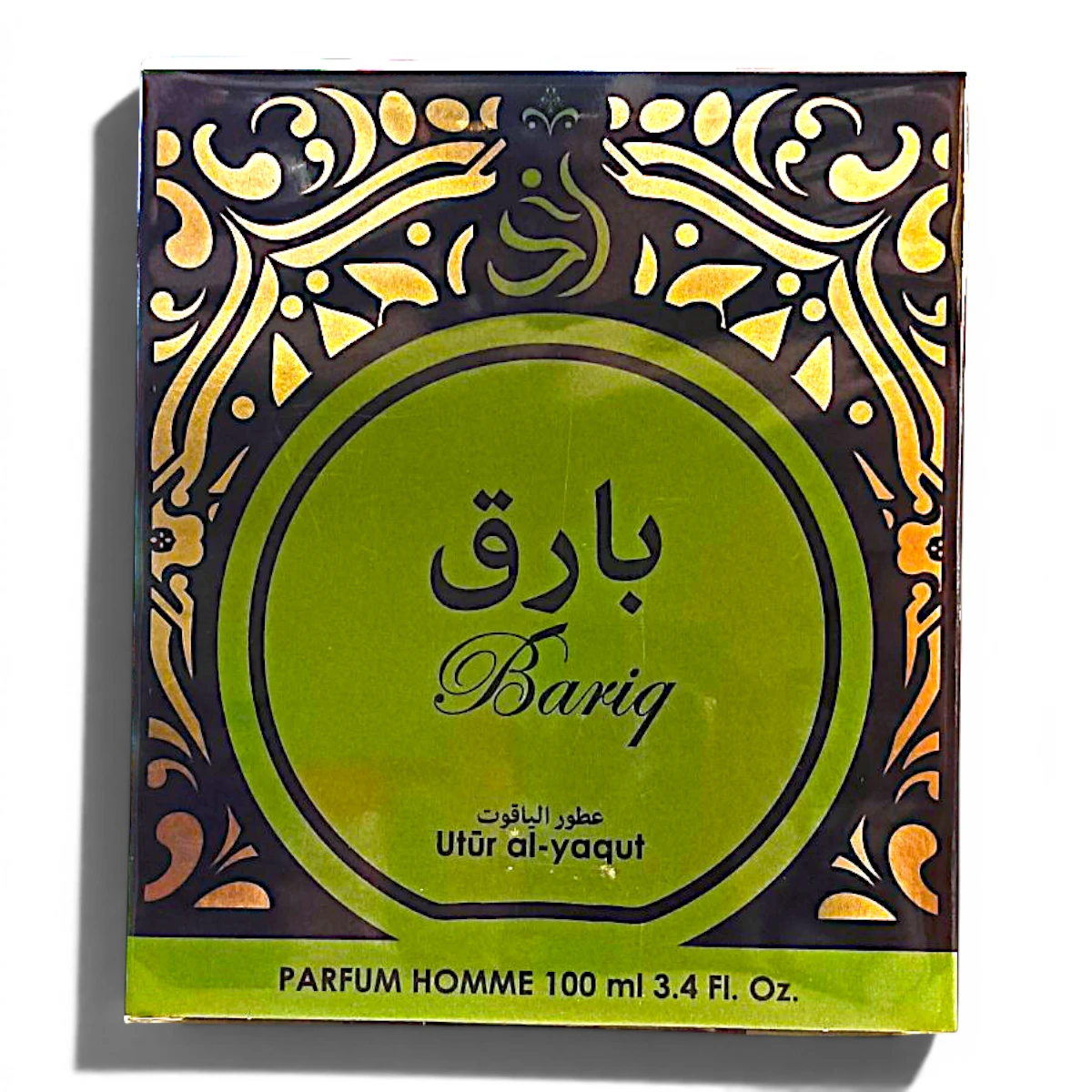 Caja de perfume verde y dorada con la etiqueta Bariq en inglés y árabe, con ornamentos dorados en los bordes. El texto dice Utūr al-yaqūt, Parfum Homme 100 ml 3.4 Fl. Oz. en inglés y árabe.