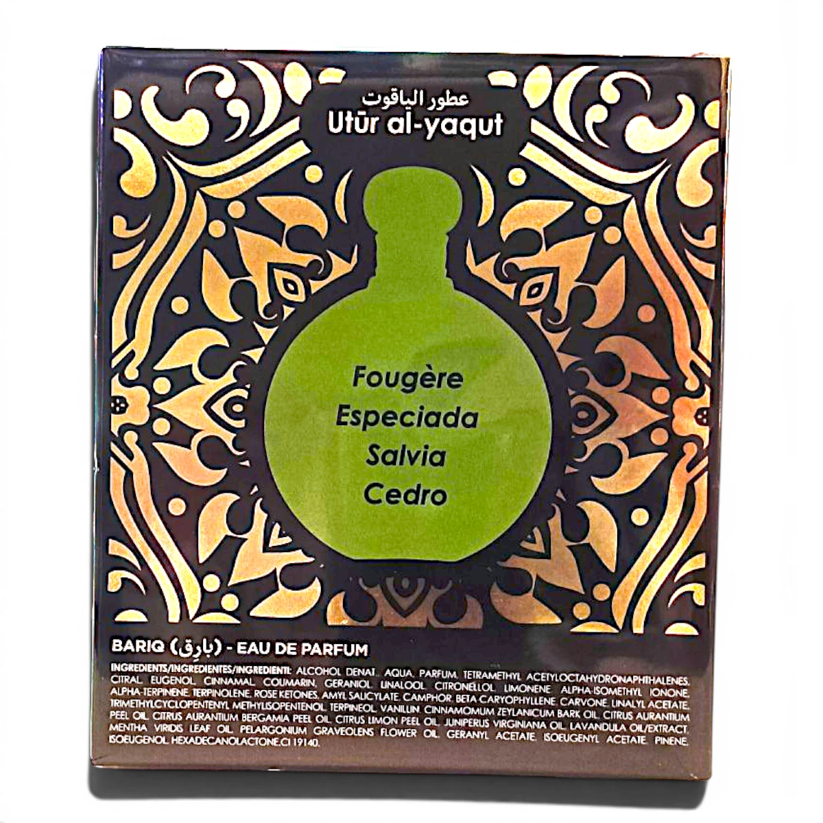 Una caja de perfume decorativa con la etiqueta Utūr al-yaqut presenta una ilustración de un frasco verde con notas olfativas: Fougère, Especiada, Salvia, Cedro. La caja presenta intrincados motivos dorados y marrones y detalles sobre los ingredientes en la parte inferior.