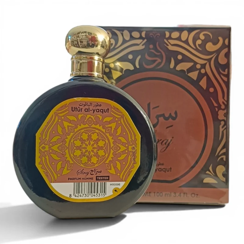 Un frasco redondo de perfume con la etiqueta Utr Al-yaqut y un tapón dorado adornado se encuentra delante de una caja decorativa. Ambos presentan intrincados motivos dorados y granates con textos en árabe e inglés.