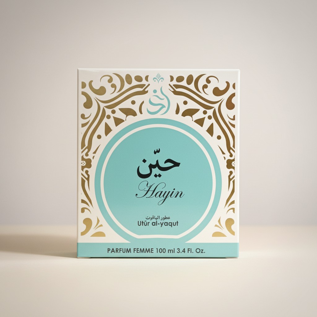 Un estuche de perfume con un diseño ornamentado en turquesa y oro muestra escritura árabe, la palabra Hayin y Utūr al-yaqūt. Indica PARFUM FEMME 100 ml 3.4 Fl. Oz. en la parte inferior.