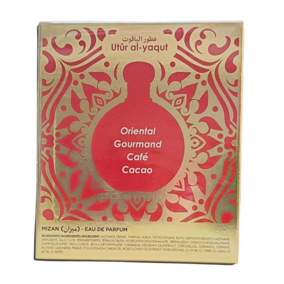 Caja de perfume dorada y roja etiquetada como Utūr al-yaqūt con un motivo decorativo, con las notas olfativas Oriental, Gourmand, Café, Cacao y los ingredientes enumerados en la parte inferior.