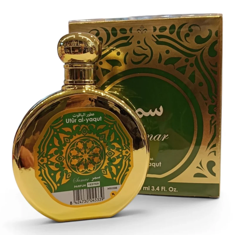 Frasco redondo de perfume dorado con la etiqueta Uttur al-yaqut y motivos decorativos verdes, delante de su caja verde y dorada a juego. El frasco contiene 3,4 onzas líquidas y lleva una etiqueta de prueba.