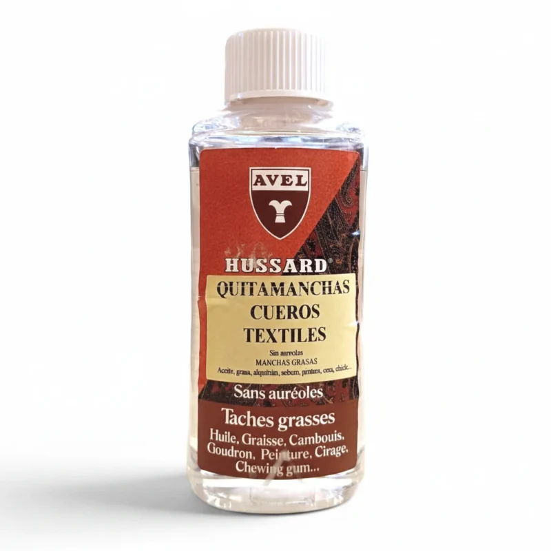 Una botella de AVEL Hussard Quitamanchas, un quitamanchas para cuero y tejidos, con una etiqueta roja y amarilla en la que se enumeran sus usos para eliminar manchas de aceite, grasa, alquitrán, pintura, cera y chicle. La botella tiene un tapón blanco.