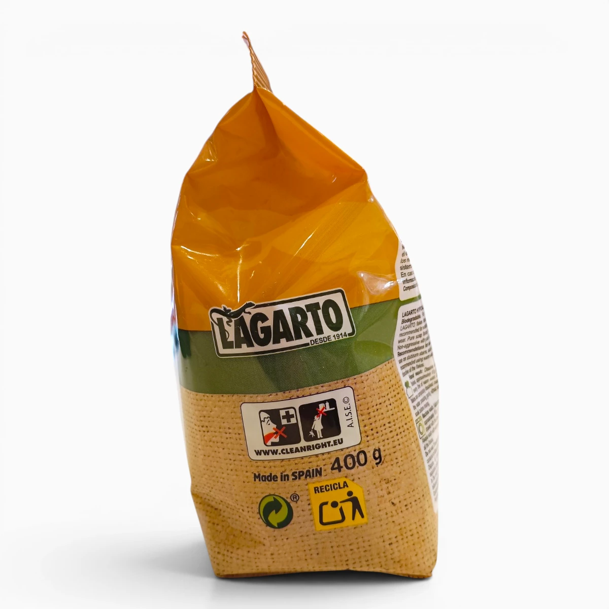 Un envase amarillo y verde de jabón Lagarto de 400 g, con la etiqueta «Fabricado en España», está colocado en posición vertical. El envase muestra los símbolos de reciclaje y un enlace a una página web, con información sobre el producto en el lateral.