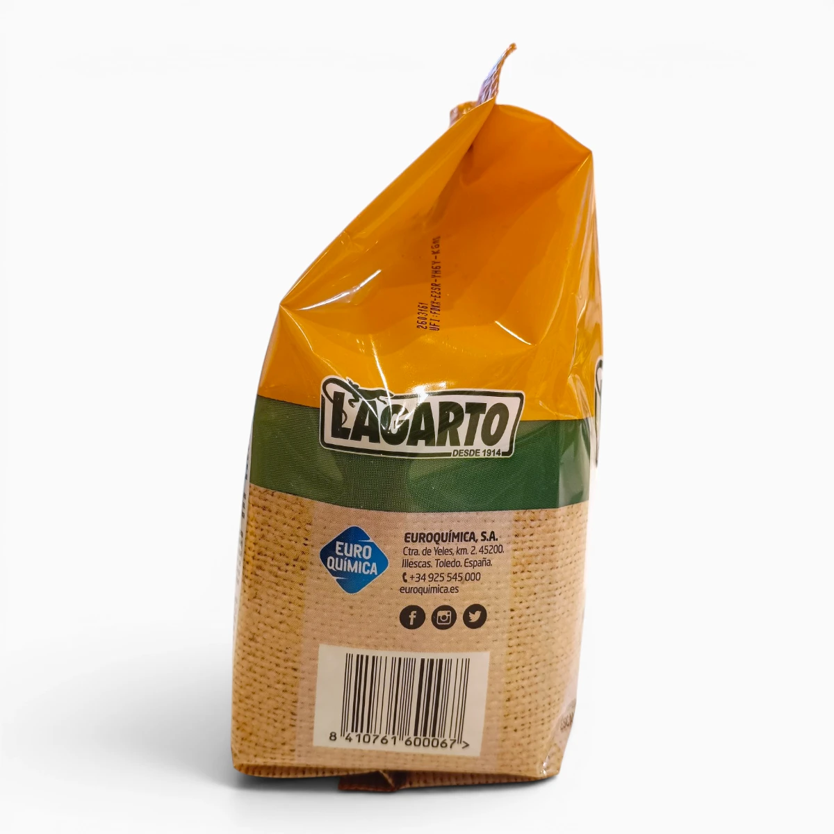 Una bolsa amarilla y verde de jabón Lagarto con un código de barras, información de contacto e iconos de redes sociales impresos en la parte trasera. El envase está parcialmente doblado y colocado en posición vertical sobre un fondo blanco.
