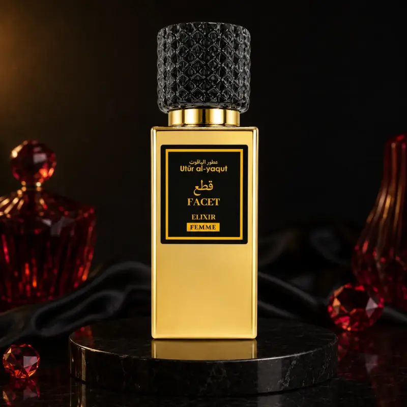 Un frasco de perfume dorado con un tapón negro texturizado en el que se lee «Utur al-Yaqut Elixir Facet Perfume Mujer 50 ml» descansa sobre una superficie de mármol negro, con adornos de cristal rojo y tela negra al fondo. Un frasco de perfume dorado con un tapón negro texturizado en el que se lee «Utur al-Yaqut Elixir Facet Perfume Mujer 50 ml» descansa sobre una superficie de mármol negro, con adornos de cristal rojo y tela negra al fondo.
